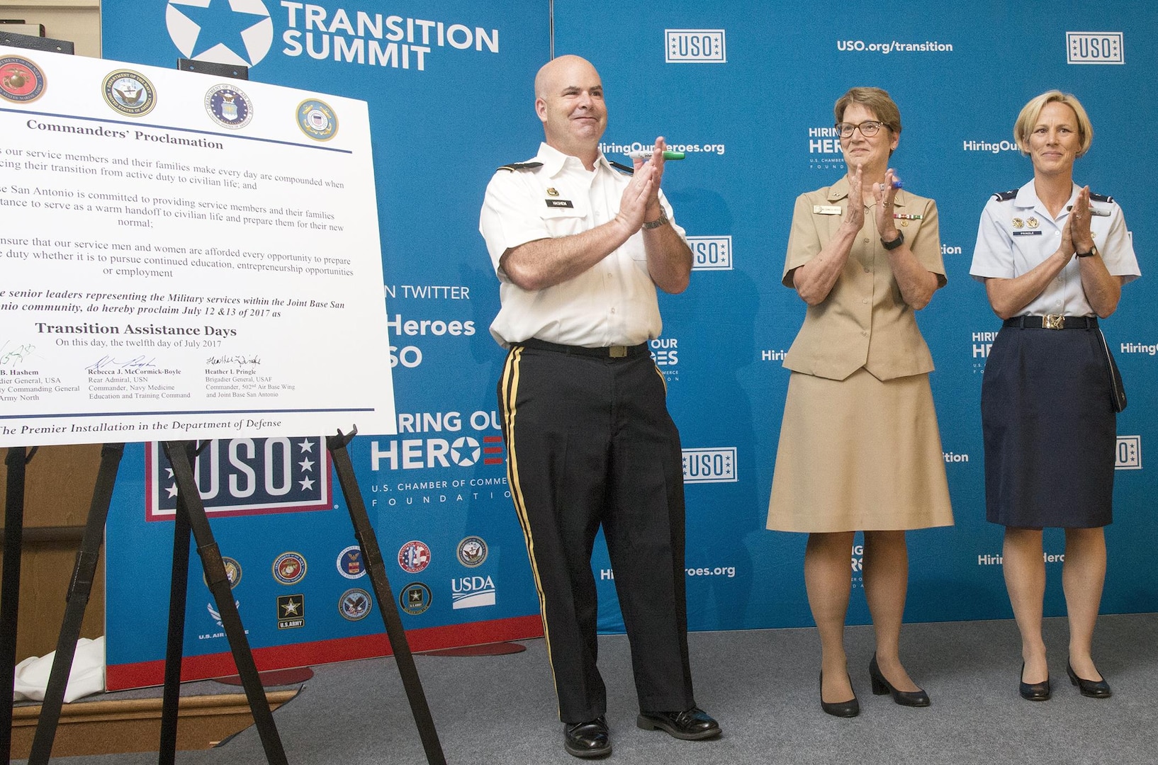 (From left) Big. Gen. John Hashem, deputy commanding general of U.S. Army North; Rear Adm. Rebecca McCormick Boyle, commander of Navy Medicine Education and Training Command; and Brig. Gen. Heather Pringle, commander of  the 502nd Air Base Wing and Joint Base San Antonio, applaud after signing the commanders' proclamation July 13 during the Transition Assistance Days at the Fort Sam Houston Community Center. 