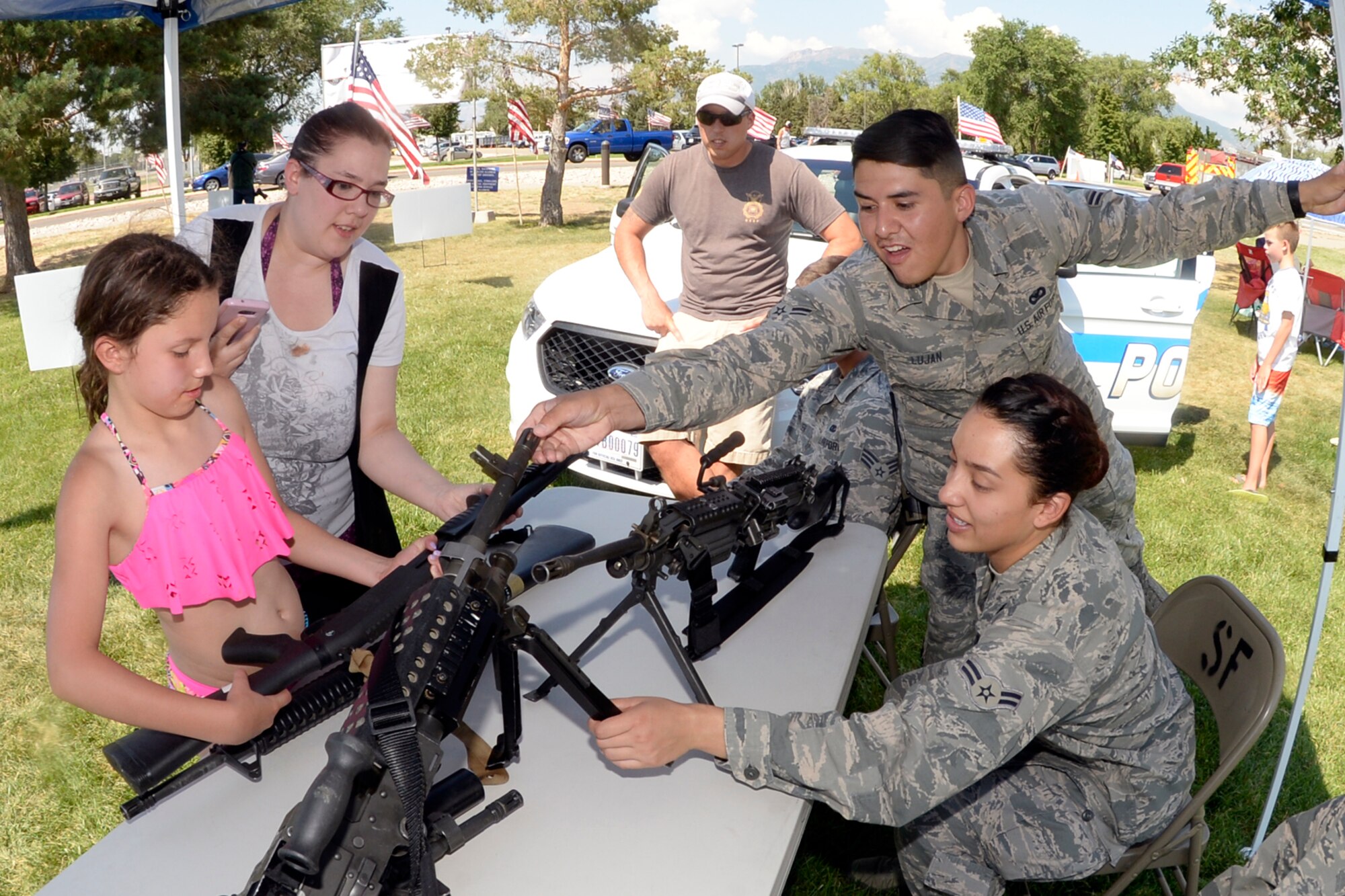 Airman 1st Class Elizabeth Tostado-paz and Airman 1st Class Andrew Lujan, both with 75th Security Forces Squadron, give visitors a chance to handle weapons during the annual Salute Picnic, July 14 at Centennial Park. The event pulled dozens of community sponsors together to provide a day of food and fun for military members and families, and showed appreciation to those who serve. (Air Force photo/Todd Cromar)