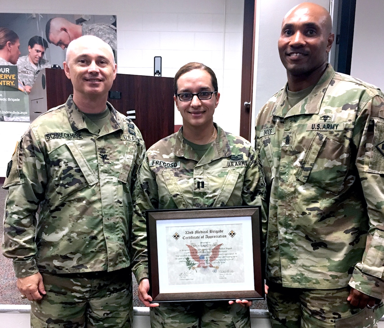 Capt. Rosita Fregoso (center), commander of Company D, 232nd Medical Battalion, accepts a certificate of appreciation for being the guest speaker at the Lesbian, Gay, Bisexual, Transgender, or LGBT, Pride Month Observance June 30, from Col. Clinton W. Schreckhise (left), 32nd Medical Brigade commander, and Command Sgt. Maj. Thomas Oates (right).
