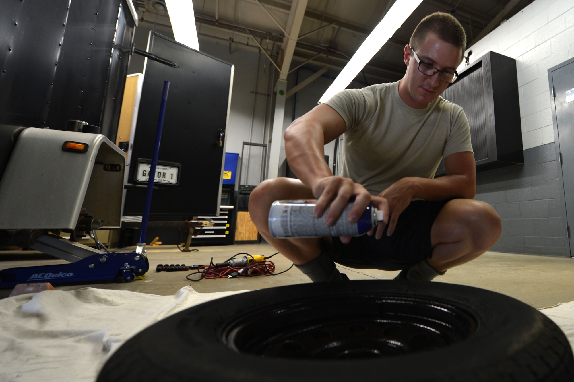 U.S. Air Force Staff Sgt. Jaron McKarns, 20th Communications Squadron radio frequency transmissions journeyman, applies spray paint to a trailer tire rim for Gator 1, at Shaw Air Force Base, S.C., July 10, 2017. Airmen assigned to the 20th CS flight maintain two trailers; Gator 1 which serves as a public announcement system trailer and Gator 2 which serves as an emergency response trailer. (U.S. Air Force photo by Senior Airman Christopher Maldonado)