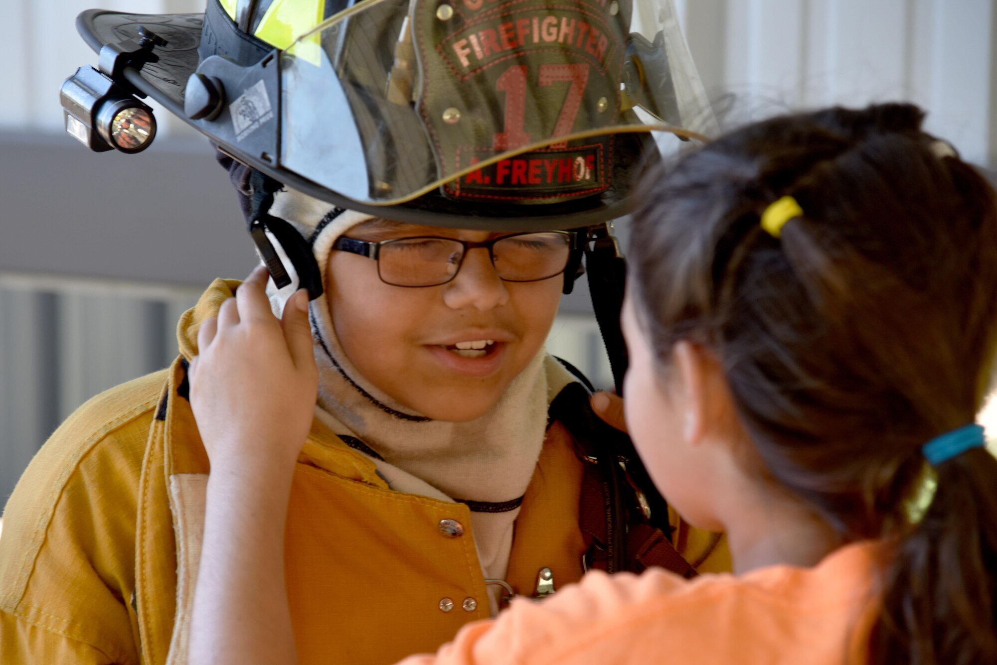 Addalynn Krickland, junior firefighter, helps Karah Teague, junior firefighter, put on a fire helmet during the junior firefighter camp at the fire station on Goodfellow Air Force Base, Texas, July 11, 2017. Krickland raced against another child to see if they could get dressed as quickly as a firefighter. (U.S. Air Force photo by Staff Sgt. Joshua Edwards/Released)