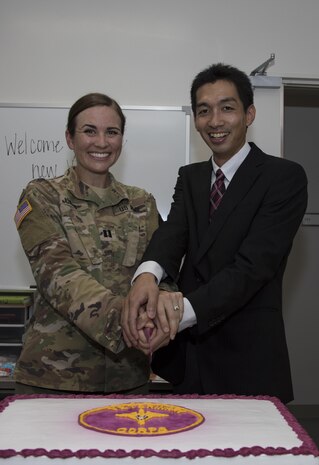 U.S. Army Capt. Monika Jones (left), branch chief, Iwakuni Veterinary Services, Public Health Activity Japan, and Dr. Shoji Tachibana (right), veterinarian, cut a ceremonial cake during the opening of the new veterinary clinic at Marine Corps Air Station Iwakuni, July 13, 2017. The new clinic took more than a year to build and will service both military working dogs and pets. (U.S. Marine Corps photo by Cpl. Joseph Abrego)
