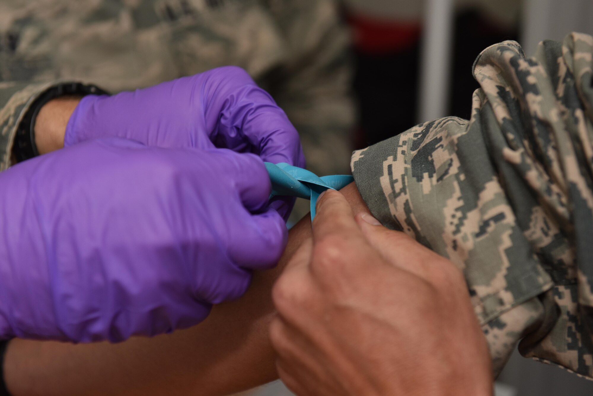 A U.S. Air Force Academy cadet practices tying a tourniquet on Tech. Sgt. Ryan Folks, 27th Expeditionary Fighter Squadron medical element, at an undisclosed location in Southwest Asia, July 6, 2017. Cadets visited the 380th Air Expeditionary Wing and embedded with multiple units across the installation to see firsthand how separate elements of the mission fit into the whole. (U.S. Air Force photo by Staff Sgt. Marjorie A. Bowlden)