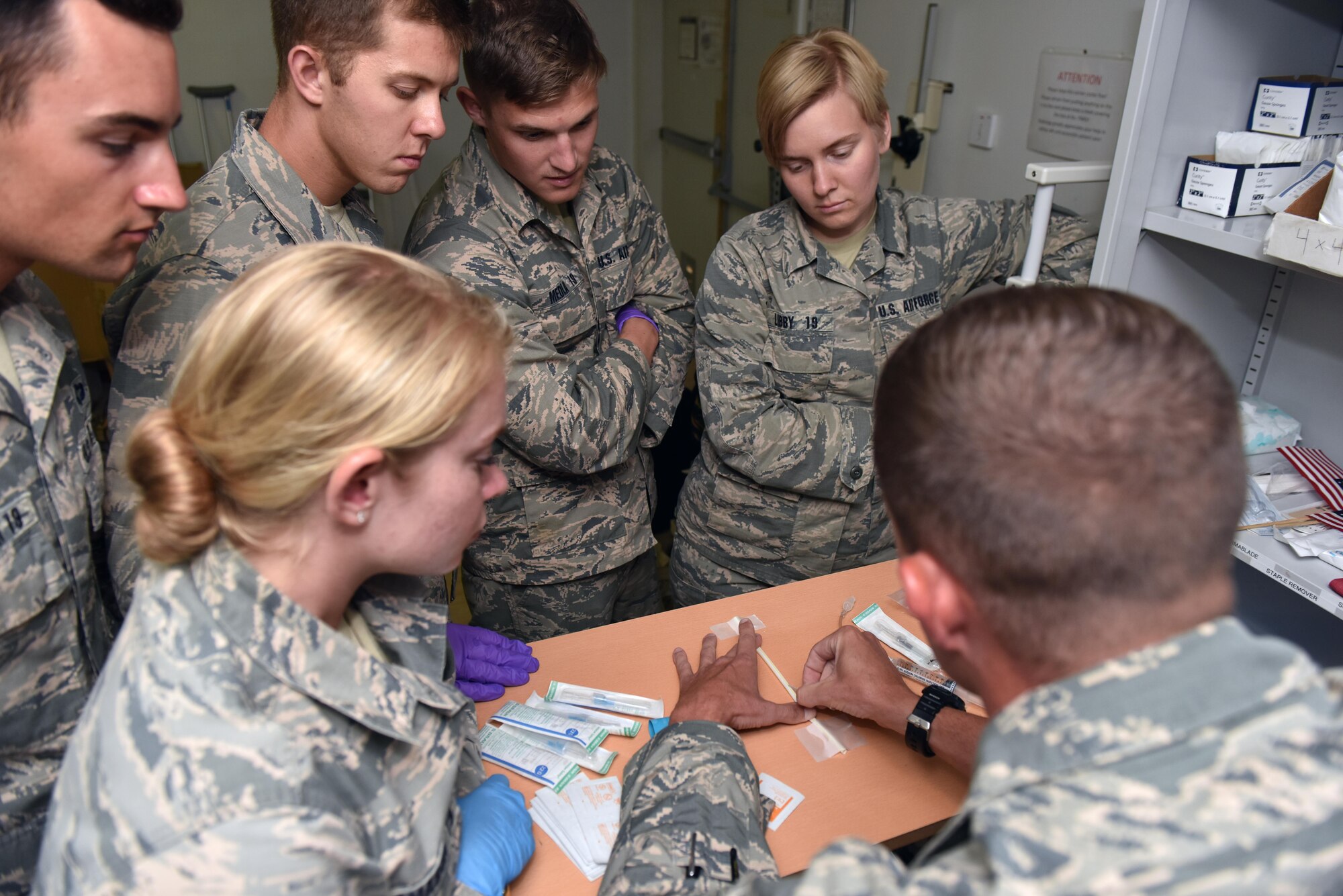 Tech. Sgt. Ryan Folks, squadron medical element of the 27th Expeditionary Fighter Squadron, demonstrates how to start an IV using a drinking straw to U.S. Air Force Academy cadets at an undisclosed location in southwest Asia, July 6, 2017. Cadets visited the 380th Air Expeditionary Wing and embedded with multiple units across the installation to see firsthand how separate elements of the mission fit into the whole. (U.S. Air Force photo by Staff Sgt. Marjorie A. Bowlden)