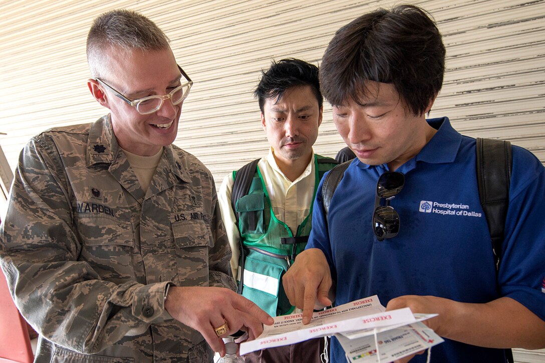 Air Force Lt. Col. Graham Warden, left, commander, 374th Medical Operations Squadron, explains an exercise inject card to emergency response personnel from Kyorin University Hospital during a major accident response exercise at Yokota Air Base, Japan, July 12, 2017. The exercise is an annual training requirement for the base to test its readiness and response capabilities and the first time Japanese emergency response personnel from Kyorin University Hospital and Japan Air Self-Defense Force members participated. Air Force photo by Yasuo Osakabe