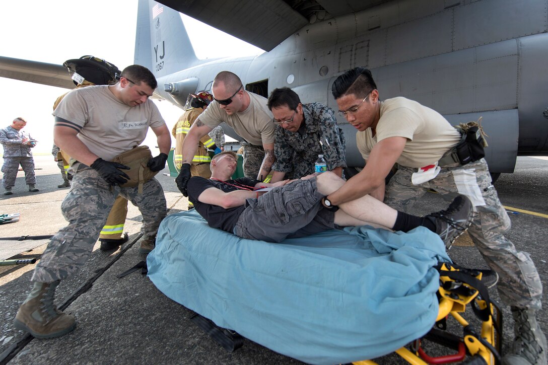 U.S. airmen and a Japanese first responder move a mock casualty onto a stretcher during a major accident response exercise at Yokota Air Base, Japan, July 10, 2017. Air Force photo by Yasuo Osakabe