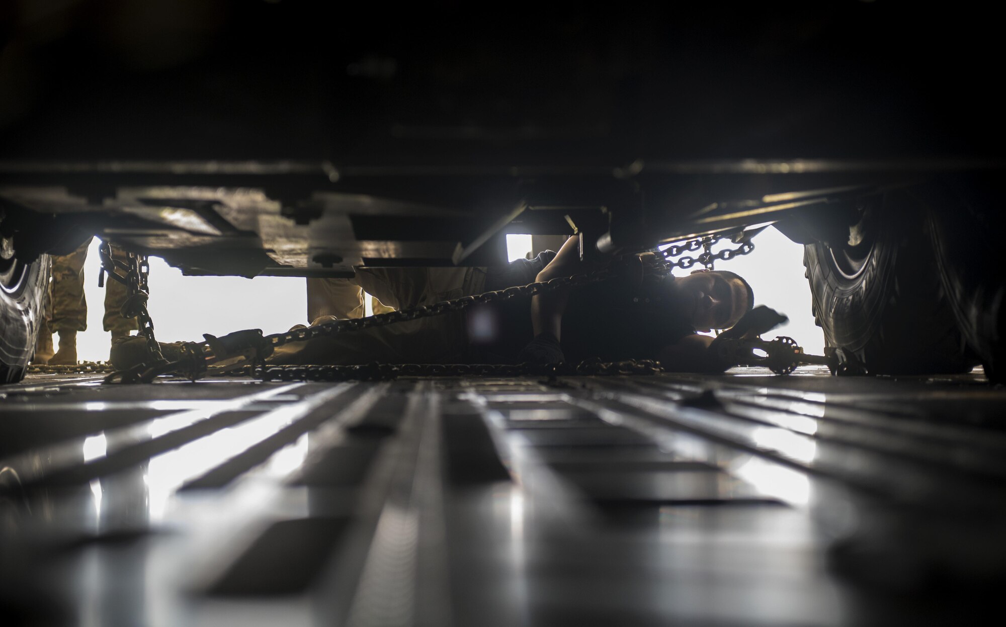 U.S. Air Force Senior Airman Tomas Cubilla, 435th Contingency Response Squadron mobile aerial port journeyman, hooks the underside of a U.S. Army 2nd Cavalry Regiment Interim Armored Vehicle Stryker to the floor of a U.S Air Force C-17 Globemaster III at Nuremburg Airport, Germany, July 13, 2017. U.S. Air Forces in Europe provides flexible and rapid airlift capability to the U.S. Army in support of vehicle repositioning, testing, and training.  (U.S. Air Force photo by Senior Airman Tryphena Mayhugh)