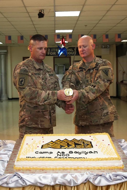 Command Sgt. Maj. Larry D. Godsey, 1st Battalion, 138th Infantry Regiment, Missouri Army National Guard, and Sgt. Maj. Andy Wilson, 3rd Medical Command-Deployment Support, prepare to cut a cake at a noncommissioned officer induction ceremony held at Camp As Sayliyah, Qatar, July 1, 2017. Thirty-eight U.S. Army Central Soldiers assigned to the 3rd Medical Command-Deployment Support, 1st Theater Sustainment Command, and the Missouri Army National Guard’s 1st Bn,138 Inf. Regt., participated in the ceremony.  (U.S. Army photo by Mr. Vincent Cummings
