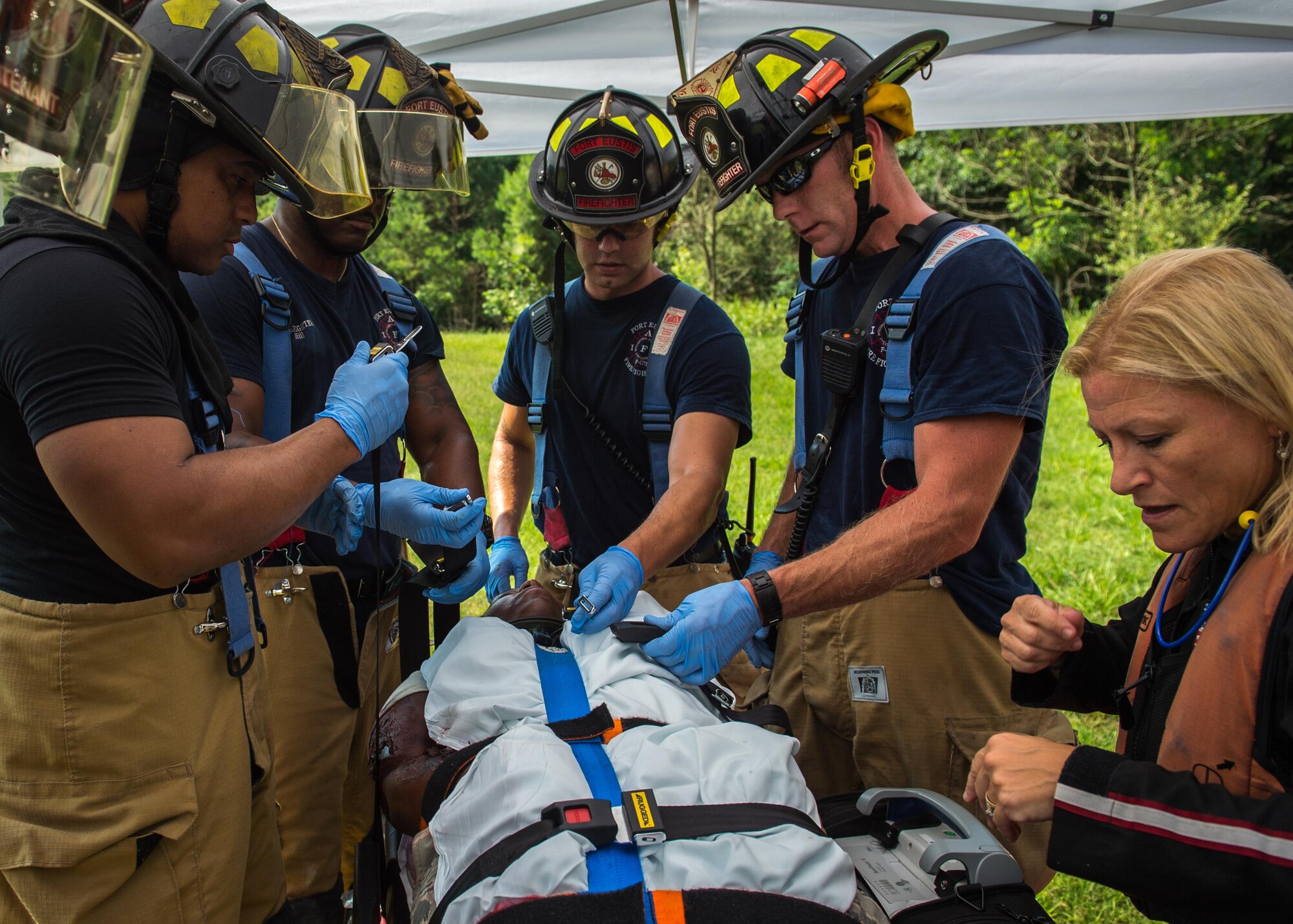 Fort Eustis Fire fighters and Nightingale Regional Air Ambulance paramedics, work together to secure a patient during an aircraft mishap exercise at Joint Base Langley-Eustis, Va., July 13, 2017. Fort Eustis conducted a helicopter crash exercise to improve its readiness for potential aircraft incidents. (U.S. Air force photo/Staff Sgt. Areca T. Bell)