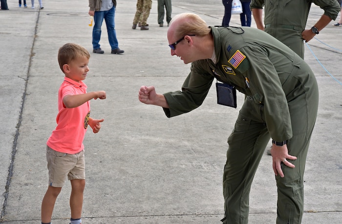 Capt. Michael Hart fist-bumps a young child at the Royal International Air Tattoo in Fairford, U.K.  A crew from the 315th Airlift Wing participated in the three-day airshow.  The airshow celebrated the 70th anniversary of the U.S. Air Force. (U.S. Air Force Photo by Maj. Wayne Capps)