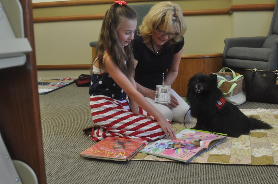 A child reads to a therapy dog during the recent Tales with Tails held at the base library.