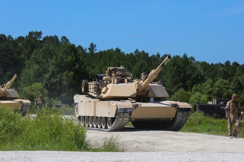 A Marine guides an M1A1 battle tank to its firing position during a combined arms range for Iron Wolf 17 at Camp Lejeune, N.C., July 14, 2017. Iron Wolf 17 is a multi-unit exercise designed to simulate battlefield conditions Marines may face while deployed. The tanks are from 2nd Tank Battalion, 2nd Marine Division. (United States Marine Corps photo by Cpl. Jon Sosner)