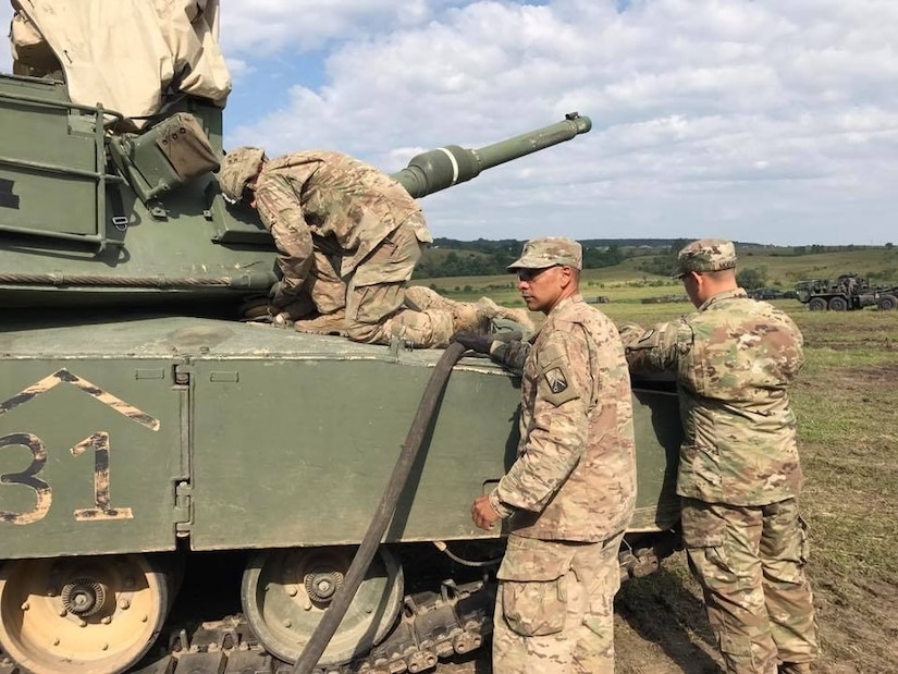 Sgt. Cruz Cotto, a motor transport operator with 515th Transportation Company, uses the retail fuel hose of the M969 5,000 gallon fuel tanker to refuel an M1 Abrams tank in Cincu, Romania on July 7.  (U.S. Army photo by 2nd Lt. Nnamdi Okangba)
