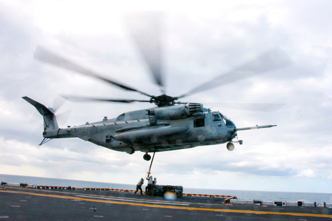 Marines attach ordnance pallets to a CH-53E Super Stallion helicopter on the flight deck of the amphibious assault ship USS Bonhomme Richard as part of a large-scale amphibious assault during exercise Talisman Saber 17 in the Coral Sea, July 13, 2017. The Marines are assigned to Combat Logistics Battalion 31, of the 31st Marine Expeditionary Unit. Navy photo by Petty Officer 2nd Class Jeanette Mullinax