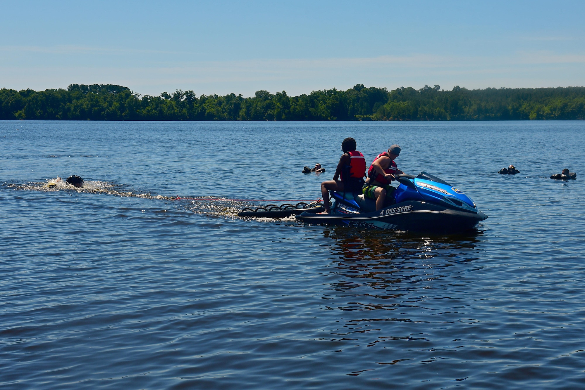 Two survival, evasion, resistance and escape augmentees drag an aircrew member during a water survival training course, June 28, 2017, at Buckhorn Reservoir, North Carolina. The Jet Ski simulates a parachute dragging the aircrew member through the water while the member must release himself from the parachute. (U.S. Air Force photo by Airman 1st Class Kenneth Boyton)