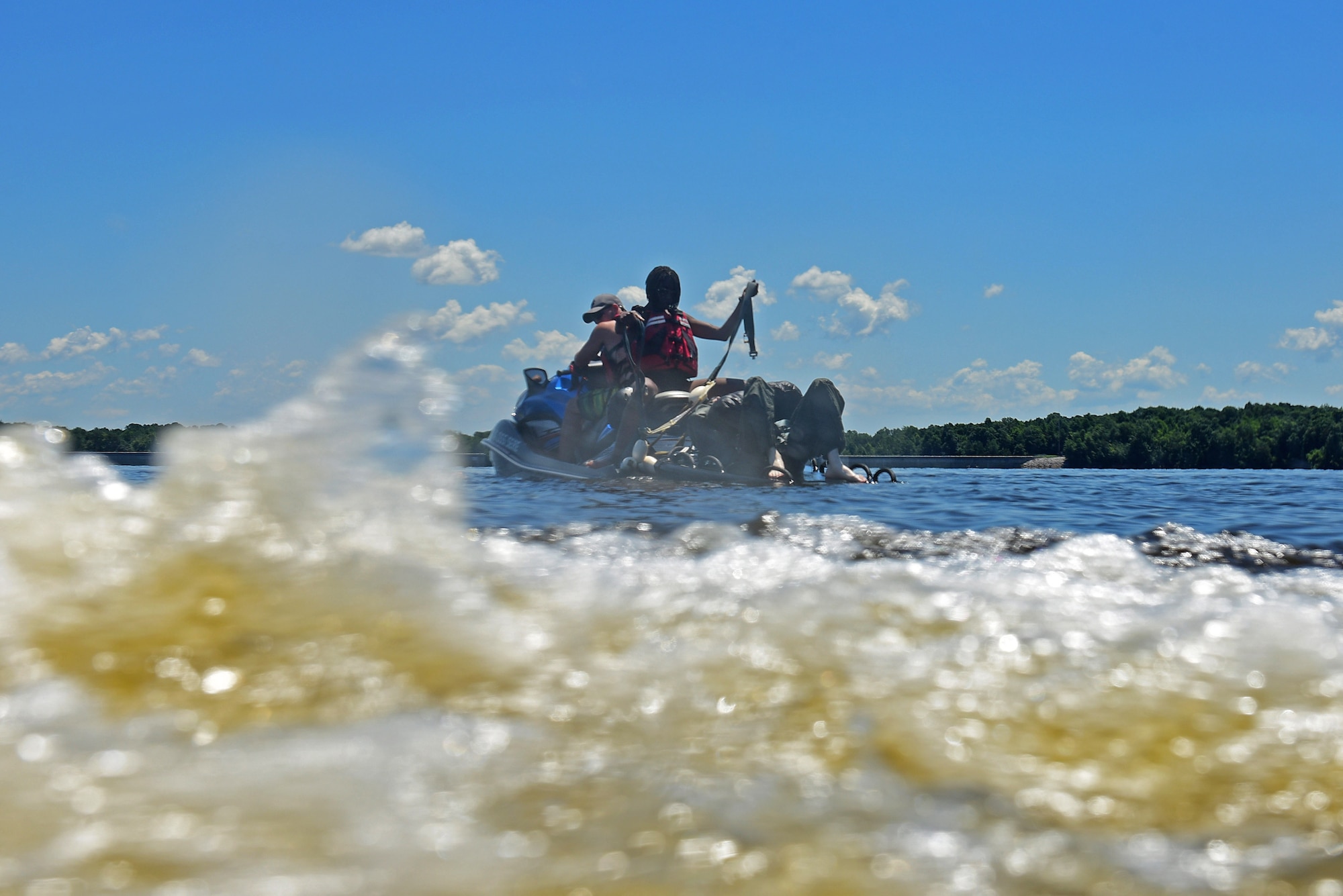 Senior Airman Aaron Ash, 4th Component Maintenance Squadron precision measurement equipment laboratory technician (left), and Airman 1st Class Angela Lambert, 4th CMS aerospace propulsion technician (middle), prepare to hook up an aircrew member to simulate a parachute drag during a water survival training course, June 28, 2017, at Buckhorn Reservoir, North Carolina. After hooking up the individual, the Jet Ski will pull them through the water at 7 mph to simulate a parachute drag. (U.S. Air Force photo by Airman 1st Class Kenneth Boyton)