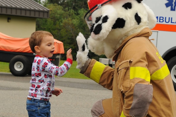 A child high-fives Sparky, the Eielson Fire Department mascot, during an open house on July 15, 2017, at Eielson Air Force Base, Alaska. Sparky greeted families as they arrived to the open house. (U.S. Air Force photo by Airman Eric M. Fisher)
