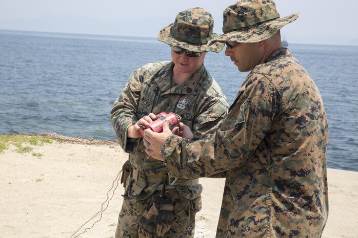 U.S. Marine Corps Staff Sgt. Chaz West, an explosive ordnance disposal (EOD) technician with Headquarters and Headquarters Squadron, and U.S. Marine Corps Chief Warrant Officer 3 Peter Scarlett, the officer in charge of EOD, examine an explosive device during a training exercise at Target Island, Marine Corps Air Station Iwakuni, Japan, July 14, 2017. The training prepares EOD Marines to handle explosive threats for any aircraft incident that may happen on the installation. (U.S Marine Corps photo by Lance Cpl. Carlos Jimenez)