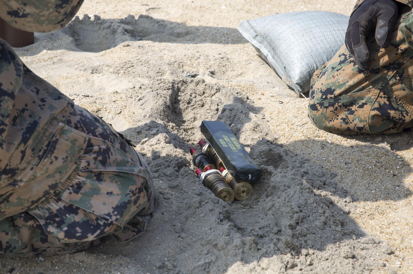 Explosive ordnance disposal Marines with Headquarters and Headquarters Squadron bury explosive devices during an emergency destruct training exercise at Target Island, Marine Corps Air Station Iwakuni, Japan, July 14, 2017. The EOD Marines spent the day burying explosive devices in the sands of the island and remotely detonating them from a bunker. Twenty pounds of composition 4 were used for every set of explosions throughout the exercise. (U.S Marine Corps photo by Lance Cpl. Carlos Jimenez)