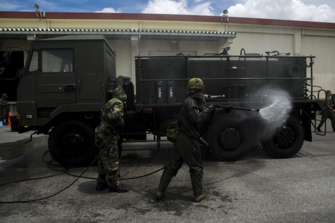 U.S. Marine Lance Cpl. Enrique Puentes Jr. sprays water on a Japanese Decontamination Truck with a Japanese Ground Self-Defense member during a simulated joint study with the JGSDF at Marine Corps Air Station Futenma on July 13, 2017. The Marines and JGSDF soldiers were integrated into one force combining U.S. and Japanese equipment while utilizing both countries’ methods of decontamination. Puentes, a native of Tampa, Florida, is a CBRN defense specialist with Marine Wing Headquarters Squadron 1, and the JGSDF soldier is with 15th Nuclear, Biological, Chemical Defense Unit (U.S. Marine Corps photo by Cpl. Kelsey Dornfeld). 