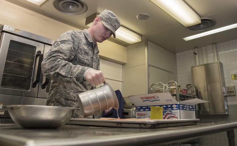 U.S. Air Force Senior Airman Jason Parks, a 35th Force Support Squadron food service technician, prepares salmon fillets in the Falcon Feeder at Misawa Air Base, Japan, July 18, 2017. The building was originally designed to be a flight kitchen, but was repurposed into a secondary dining facility later on. (U.S. Air Force photo by Airman 1st Class Sadie Colbert)