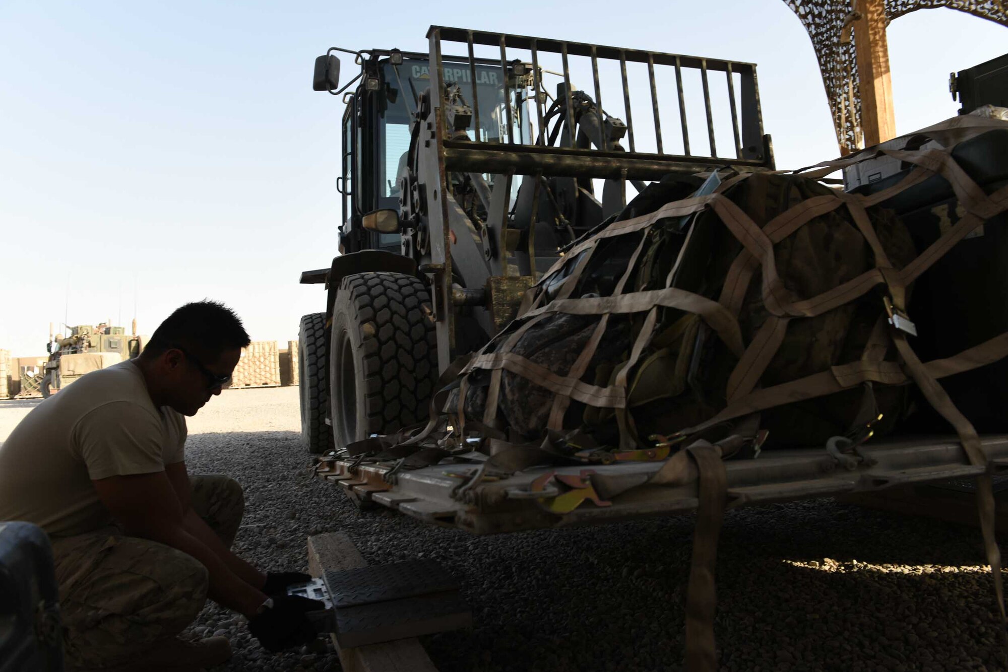 U.S. Air Force Senior Airman Tristan Gavia, an air transportation specialist deployed in support of Combined Joint Task Force – Operation Inherent Resolve and assigned to the 442nd Air Expeditionary Squadron, places a weigh scale under a cargo pallet at Qayyarah West Airfield, Iraq, July 2, 2017. The aerial porters worked together with their joint service partners to create a 32,000 square foot cargo grid yard with a shaded cargo build-up area for the aerial port team to build pallets and inventory cargo. CJTF-OIR is the global Coalition to defeat ISIS in Iraq and Syria.   (U.S. Air Force photo by Tech. Sgt. Jonathan Hehnly)