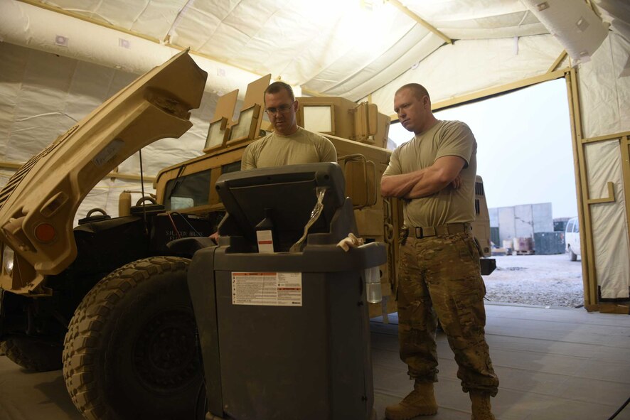 U.S. Air Force Staff Sgts. Adam Martin, a fire truck maintenance specialist, and Shawn Benton, an aerospace ground equipment craftsman, both deployed in support of Combined Joint Task Force – Operation Inherent Resolve and assigned to the 370th Air Expeditionary Advisory Group, Detachment 1, use a refrigerant recovery station to perform a leak test and charge the air conditioning system of a Humvee inside the vehicle maintenance tent at Qayyarah West Airfield, Iraq, July 2, 2017. The new vehicle maintenance facility improved efficiency for the maintainers as they can now not only get out of the sun to work on their vehicles, but also complete tasks during all hours of the day. CJTF-OIR is the global Coalition to defeat ISIS in Iraq and Syria.  (U.S. Air Force photo by Tech. Sgt. Jonathan Hehnly)