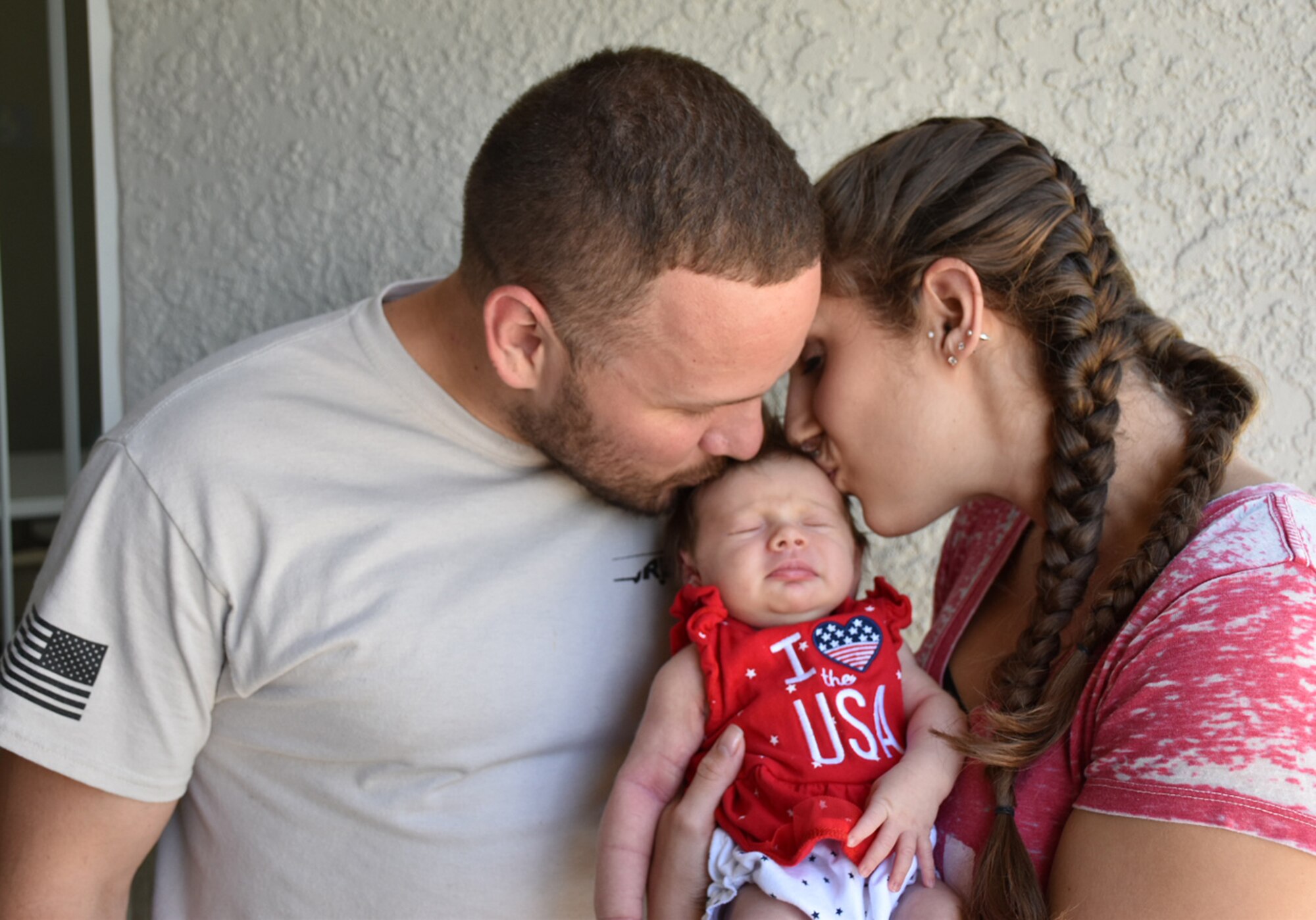 Staff Sgt. Jeff A. Parrish Jr., left, 920th Aircraft Maintenance Squadron aircraft armament systems technician, and his wife, Jacquelyne Parrish, kiss their daughter Raelynn Noelle Parrish, July 4, 2017, outside of their home in Ocoee, Florida. Jeff returned home shortly before the early birth of their first child after a four-month deployment to Afghanistan. (Courtesy photo) 