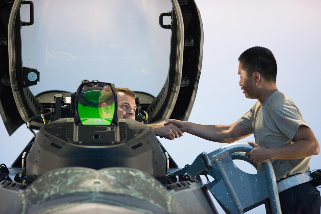 U.S. Air Force Airman 1st Class Andy Luong, 1st Aircraft Maintenance Squadron crew chief, shakes hands with a 94th Fighter Squadron pilot prior to his departure from Joint Base Langley-Eustis, Va., July 11, 2017. Pilots assigned to the 1st Fighter Wing participate in night flying operations to maintain currency on use of night vision while flying. (U.S. Air Force Photo/Master Sgt. Benjamin Wilson)