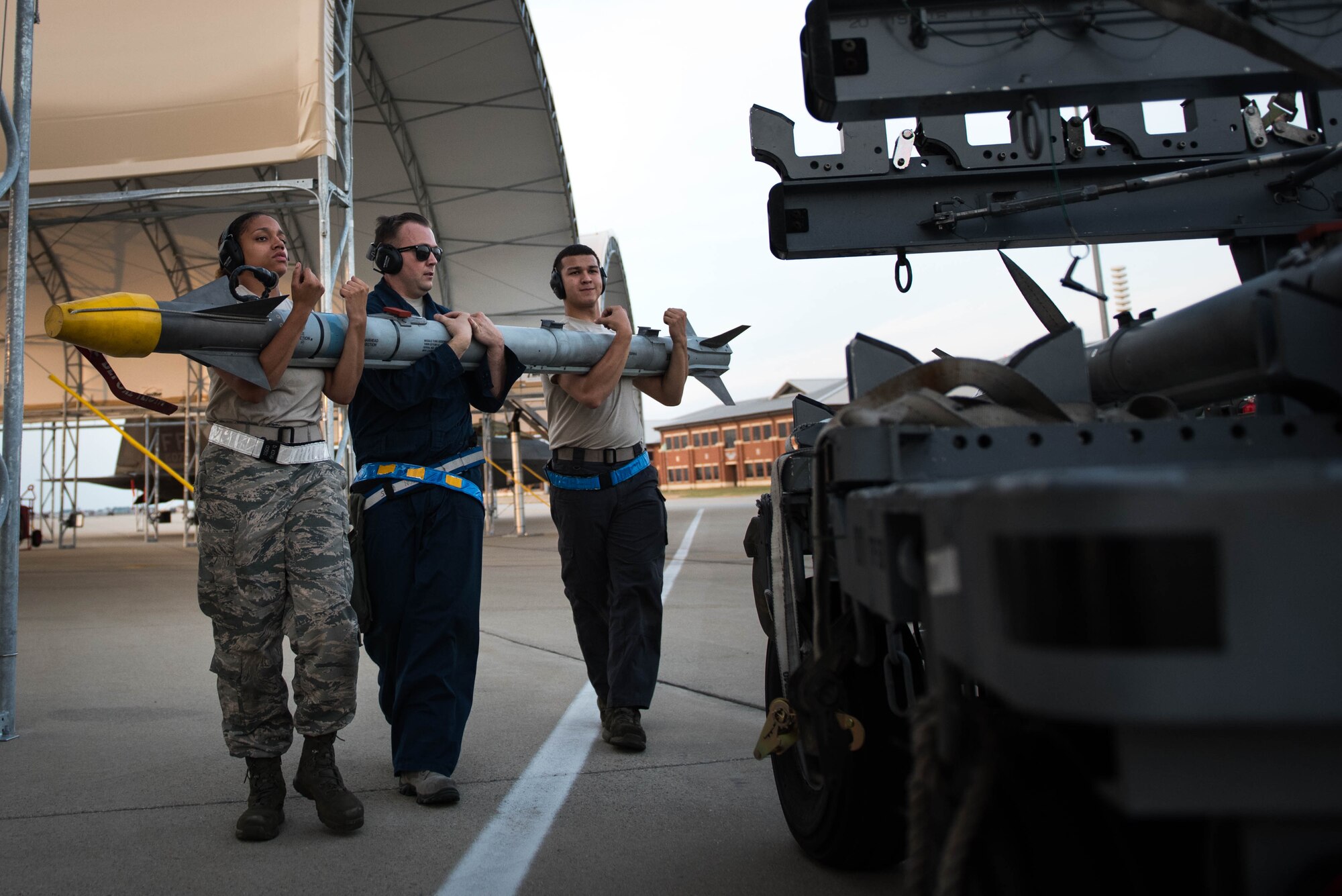 (From Left) U.S Air Force Airman First Classes Dianna King and Manuel Garcia, and Staff Sgt. Jonathan Deacon, 1st Aircraft Maintenance Squadron weapons load crew team members, load munitions onto a munitions cart during night operations at Joint Base Langley-Eustis, Va., July 11, 2017. Night operations give all squadrons a chance to perfect their skills and movement in a nighttime environment. (U.S. Air Force photo/Staff Sgt. Carlin Leslie)