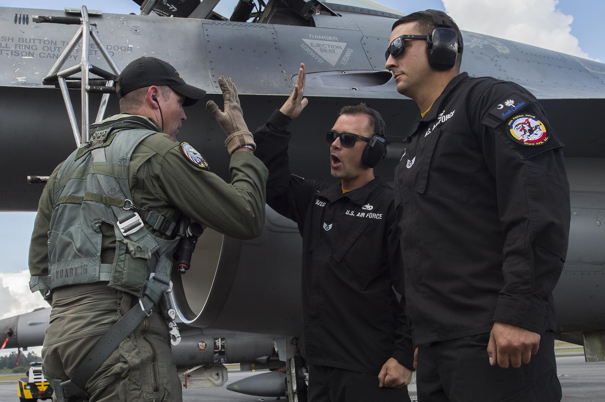 Maj. John “Rain” Waters, Air Combat Command F-16 Viper Demonstration Team commander and pilot, left, performs a handshake with Staff Sgt. Dominic Dizes, ACC F-16 Viper Demonstration Team crew chief, center, while Tech. Sgt. Stephen Mullins, ACC F-16 Viper Demonstration Team avionics specialist, right, stands at attention following an aerial demonstration at the F-AIR COLOMBIA 2017 air show in Rionegro, Colombia, July 16, 2017. The demonstration team represents the U.S. Air Force at more than 20 air shows annually, inspiring the next generation of Airmen both at home and abroad. (U.S. Air Force photo by Staff Sgt. Zade Vadnais)