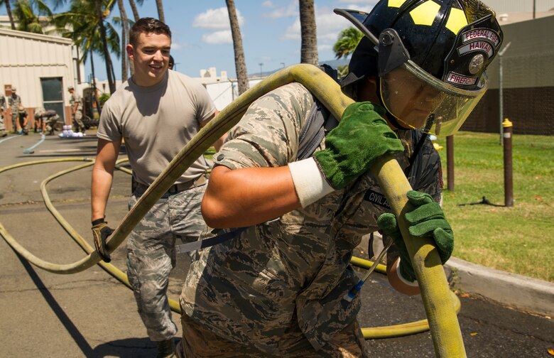 Axton Ching, Civil Air Patrol cadet, carries a fire hose with Senior Airman Louie Saiz, 647th Civil Engineering Squadron firefighter, during a Civil Air Patrol visit to the 15th Wing as part of their encampment, Joint Base Pearl Harbor-Hickam, Hawaii, July 14, 2017. Encampment is a week-long program, during which cadets are immersed into a modified Air Force basic training environment. Cadets learned the basics of military life with physically and mentally challenging activities. (U.S. Air Force photo by Tech. Sgt. Heather Redman)