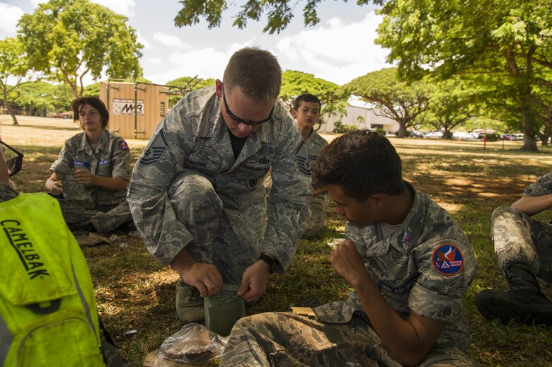 Master Sgt. Brian Helems, Joint Base Security non-commissioned officer in charge of operations, helps a cadet open his meal during the Civil Air Patrol's visit to the 15th Wing as part of their encampment, Joint Base Pearl Harbor-Hickam, Hawaii, July 14, 2017. Encampment is a week-long program, during which cadets are immersed into a modified Air Force basic training environment. Cadets learned the basics of military life with physically and mentally challenging activities. (U.S. Air Force photo by Tech. Sgt. Heather Redman)