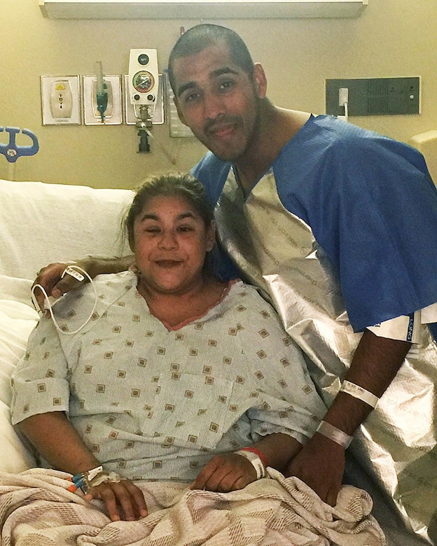 An airman embraces a woman in a hospital bed.