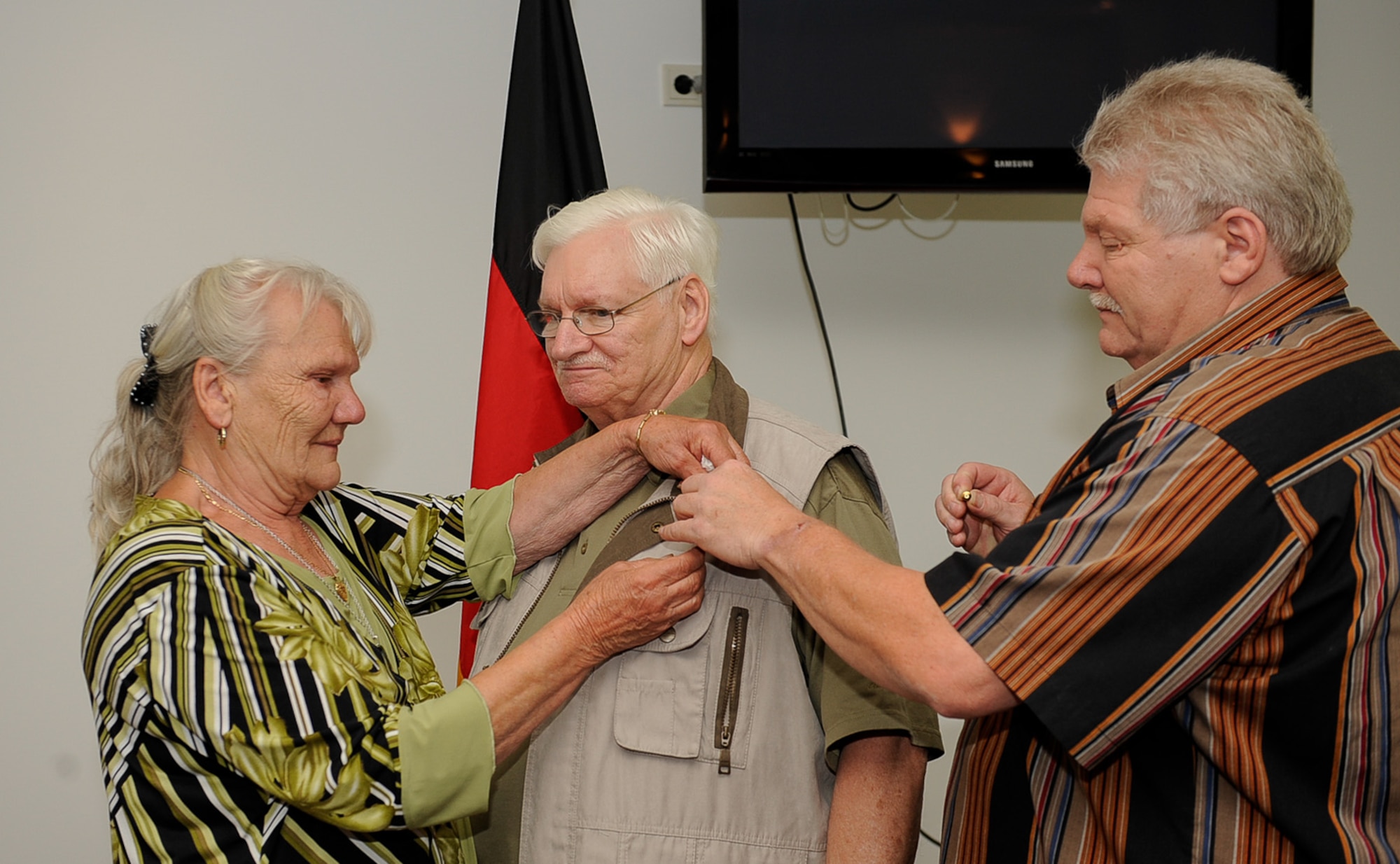 Thomas Perry (middle), retired from the 786th Force Support Squadron after 48 years of service, receives an award presented by his wife and son at the Lindberg Hof Dining Facility, Kapaun Air Station, June 30, 2017. Retiring at the top of his game, Mr. Perry was the Lindberg Hof Dining Facility’s top chef the last nice years before his retirement. (U.S. Air Force photo by Airman 1st Class Savannah L. Waters)