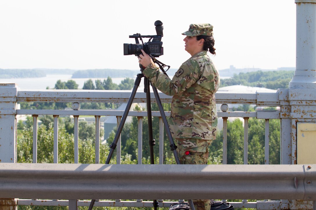 Sgt. Charity Boedeker, broadcaster with 457th Civil Affairs Battalion, 361st Civil Affairs Brigade, prepares her camera on the Danube Bridge from the Bulgarian side prior to the 2nd Cavalry Regiment bridge crossing in Ruse, Bulgaria, July 17 (U.S. Army Reserve photo by Capt. Jeku Arce, 221st Public Affairs Detachment).