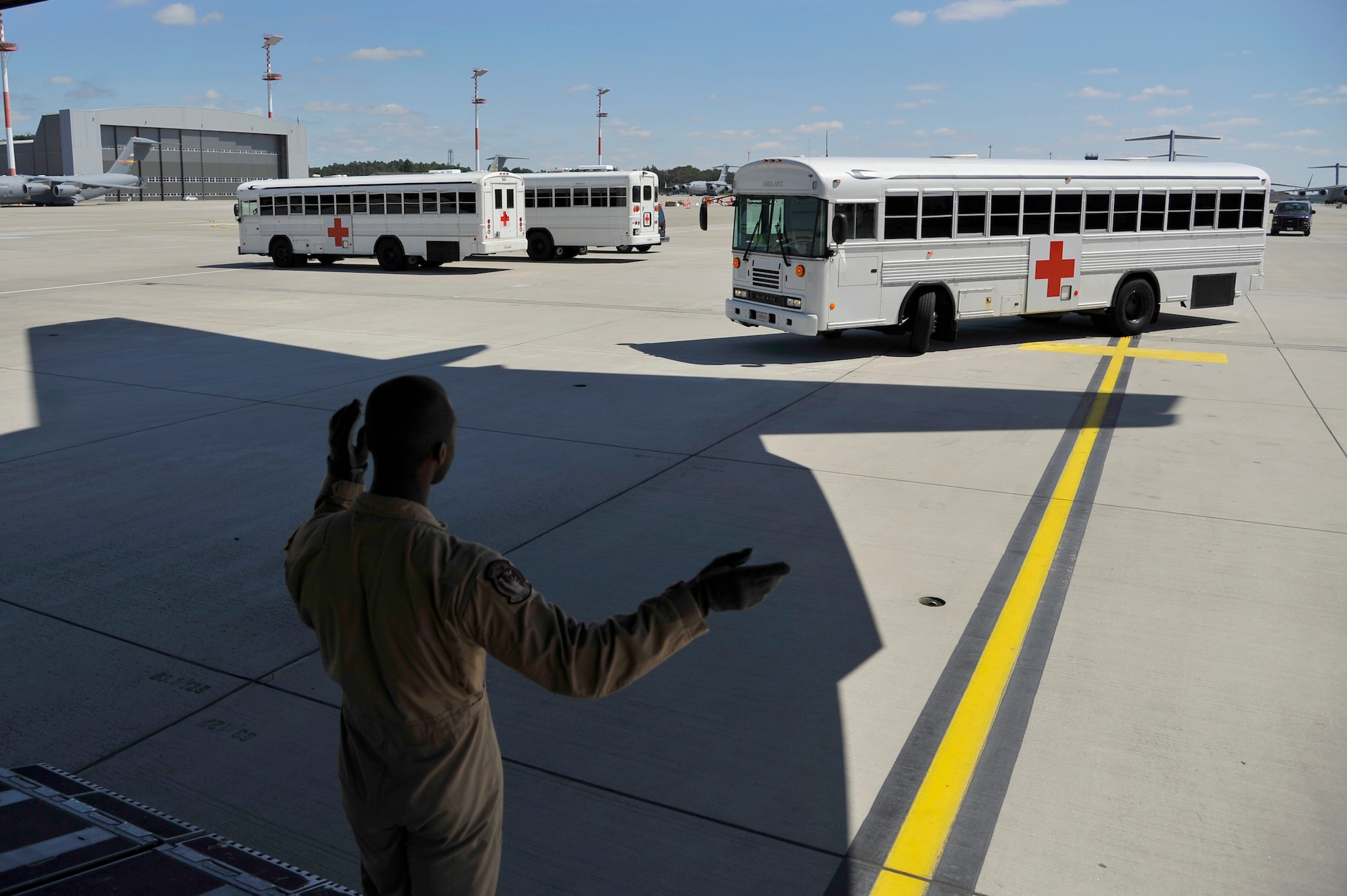 U.S. Air Force Staff. Sgt. Jeremy McCray, 105th Airlift Wing C-17 Globemaster III loadmaster, signals an ambulance bus away during a patient move on Ramstein Air Base, Germany, July 13, 2017. Mission frequencies vary, however, En-route Patient Staging Facility personnel perform between two and 10 patient moves on a weekly basis. (U.S. Air Force photo by Airman 1st Class D. Blake Browning)