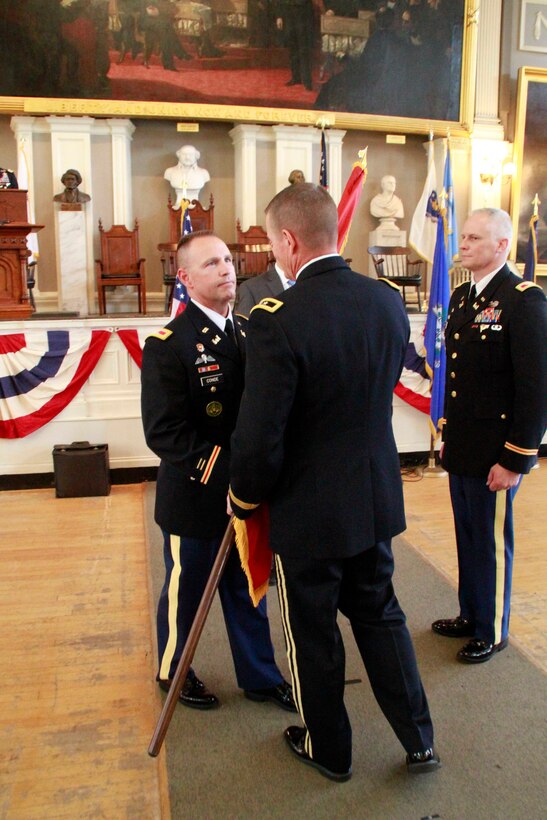 U.S. Army Maj. Gen. Kent Savre, commanding general, Maneuver Support Center of Excellence and Fort Leonard Wood, Mo., passes the Corps flag to Col. William M. Conde, the incoming district engineer and commander of U.S. Army Corps of Engineers New England District during the change of command ceremony at Faneuil Hall, in Boston, Mass., July 19, 2017. Conde assumed command from Col. Christopher Barron (right), the outgoing district engineer and commander during the ceremony. (U.S. Army photo by Diallo Ferguson/Released)