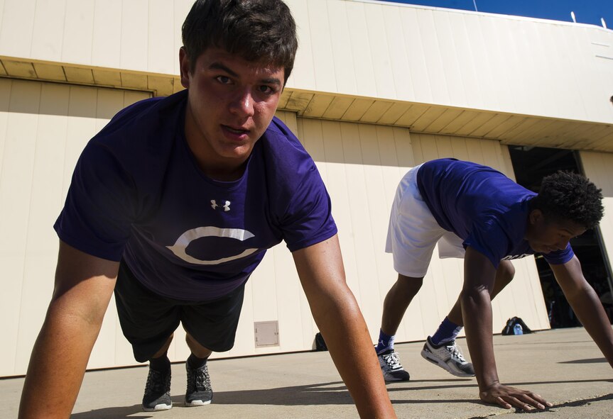 Clovis High School football players exercise on the flightline during their tour at Cannon Air Force Base, NM, July 19, 2017. From practicing physical form on the flightline to sweating through sets in the gym, the students followed a regimen that special tactics Airmen use to maintain a high standard of physical ability. (U.S. Air Force photo by Senior Airman Lane T. Plummer)