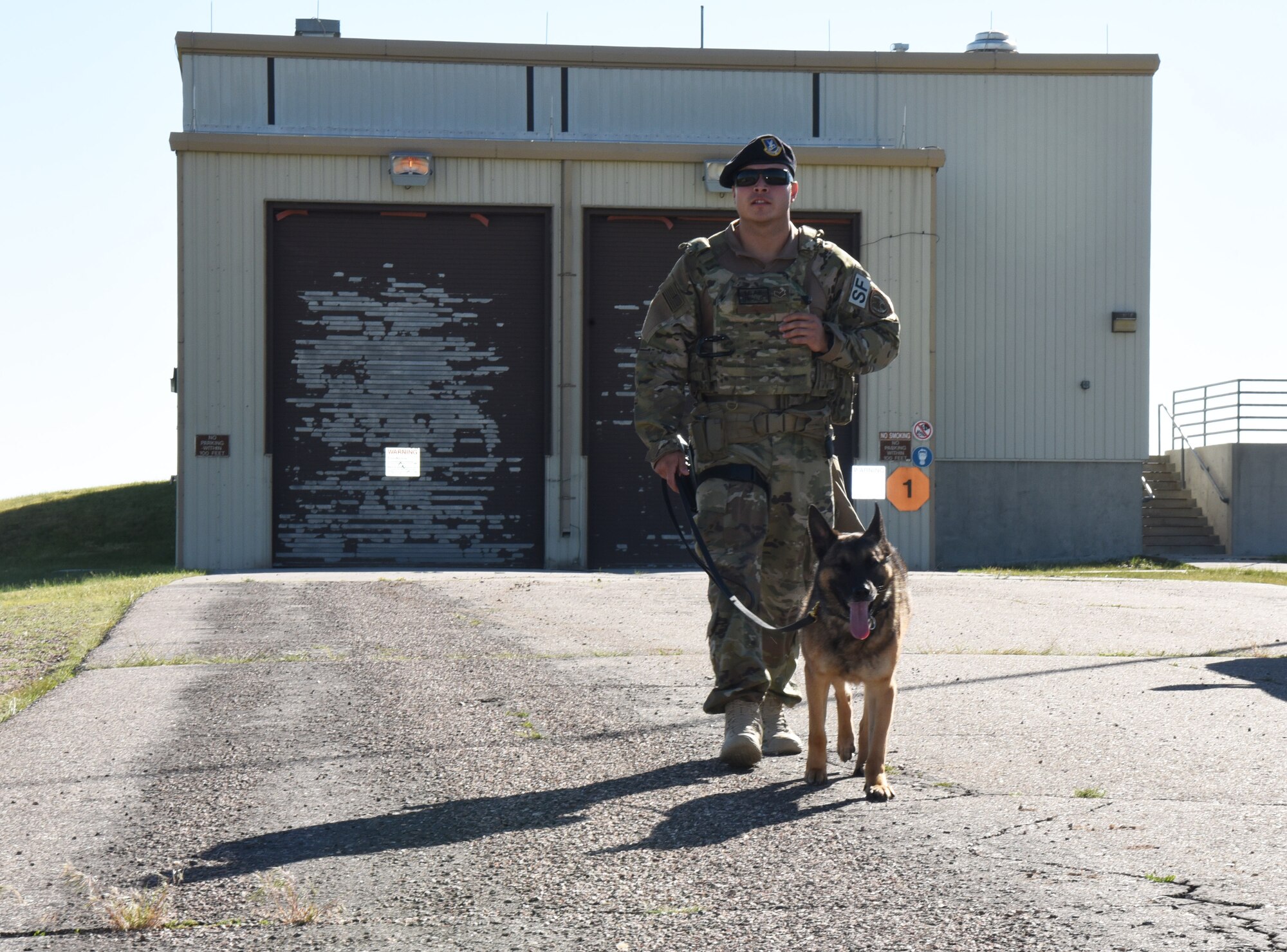 Staff Sgt. Richard Garcia, 90th Security Forces Squadron dog handler, walks back with his K-9 after doing a security check in a building at F.E. Warren Air Force Base, Wyo., July 14, 2017. Defenders from the 90th SFS are alerted by the Base Defense Operations Center when any alarms go off on base. (U.S. Air Force photo by Airman 1st Class Breanna Carter)