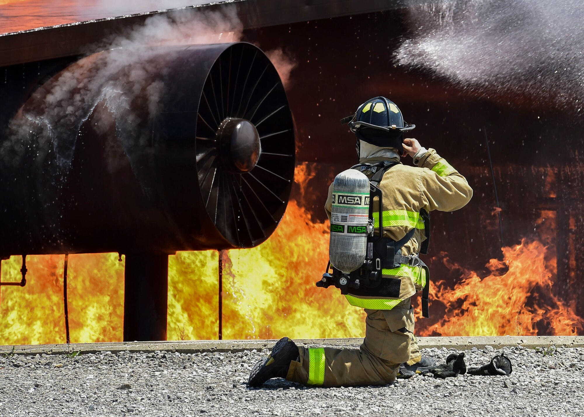 An Army firefighter of the 5694th Engineer Detachment from the Army National Guard stationed in Mansfield, Ohio, straps on his fire helmet after donning his gas mask during an airport rescue firefighting exercise July 18, 2017, here. The 5694th is at YARS for one week while completing their annual training. (U.S. Air Force Photo/Senior Airman Jeffrey Grossi)