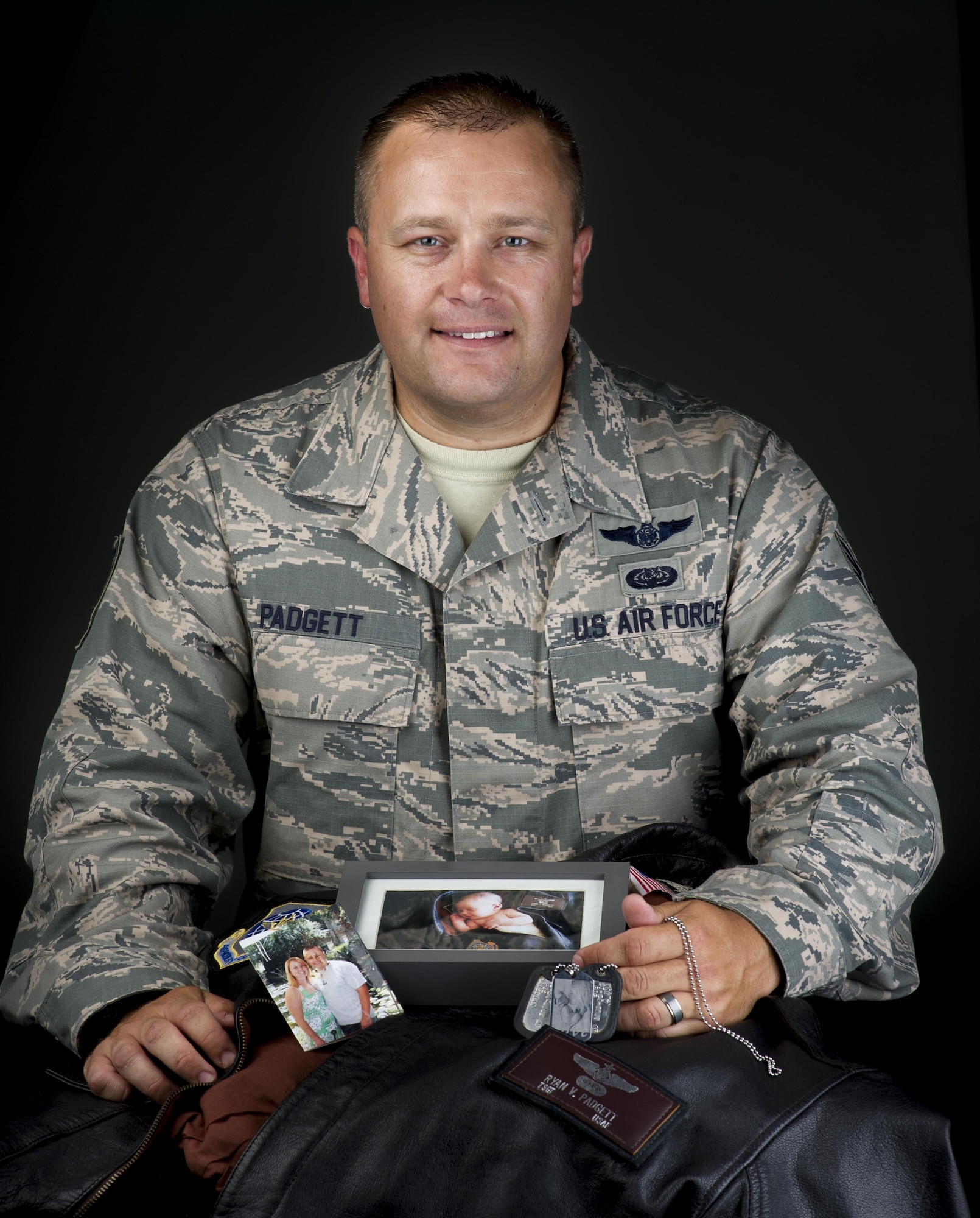 Tech. Sgt. Ryan Padgett, 570 Global Mobility Squadron unit training manager, displays the keepsakes that travel along with him on his worldwide missions, July 18, 2017. Men and women serving their country in all branches of the military have traditionally kept meaningful mementos or talismans close to them for good luck, as reminders, to bring comfort or other deeply felt personal reasons. Digitaly altered for security reasons. SSN blurred in camera RAW. (U.S. Air Force photo Illustration/Heide Couch)