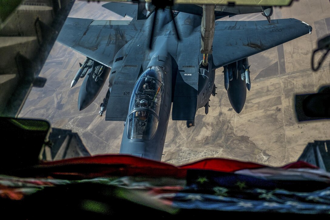 A fighter jet appears receives fuel from the boom of another aircraft while in flight.