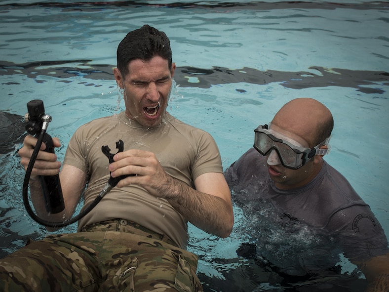 Staff Sgt. Anthony Fischer, right, a survival, evasion, resistance and escape specialist with the 1st Special Operations Support Squadron, supervises as a pilot with the 8th Special Operations Squadron surfaces after testing his oxygen tank under water during rotary wing water survival training at Hurlburt Field, Fla., July 18, 2017. More than 10 aircrew members performed emergency exit procedures while submerged under water in a simulated inverted helicopter crash. (U.S. Air Force photo by Airman 1st Class Joseph Pick)