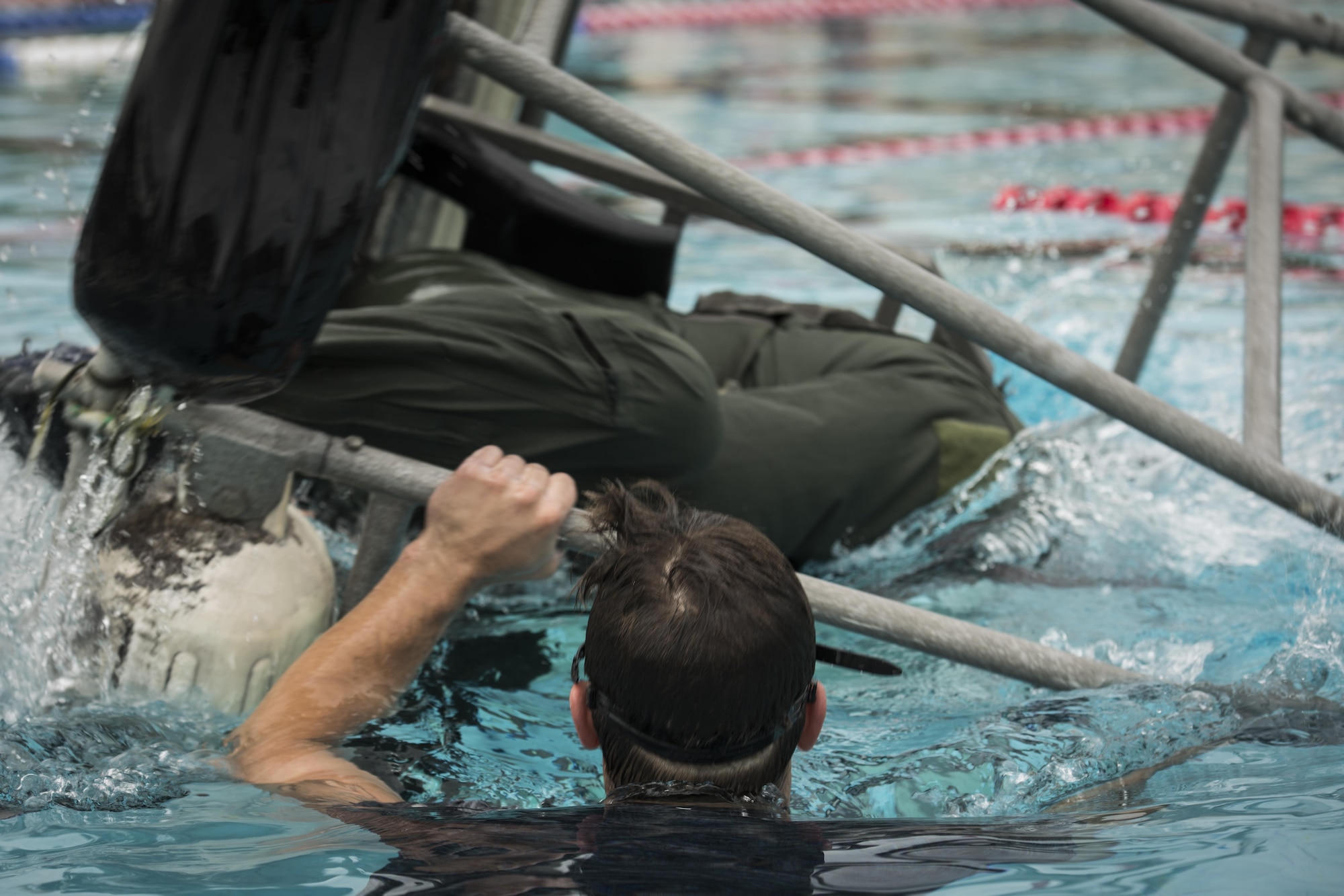 A survival, evasion, resistance and escape specialist with the 1st Special Operations Support Squadron flips a shallow water egress trainer chair during rotary wing water survival training at Hurlburt Field, Fla., July 18, 2017. The SWET chair allows aircrew members to practice escape procedures while submerged under water during a simulated inverted helicopter crash. (U.S. Air Force photo by Airman 1st Class Joseph Pick)