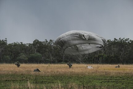 Paratroopers of 4th Infantry Brigade Combat Team (Airborne) 25th Infantry Division, move to a parachute collection zone while another lands in Shoalwater Bay, Queensland, Australia, July 13. The airborne operation was conducted as part of Exercise Talisman Sabre 2017, a massive, biennial exercise designed to exercise the partnership of joint forces throughout the Pacific region. (U.S. Army photo by Staff Sgt. Daniel Love)