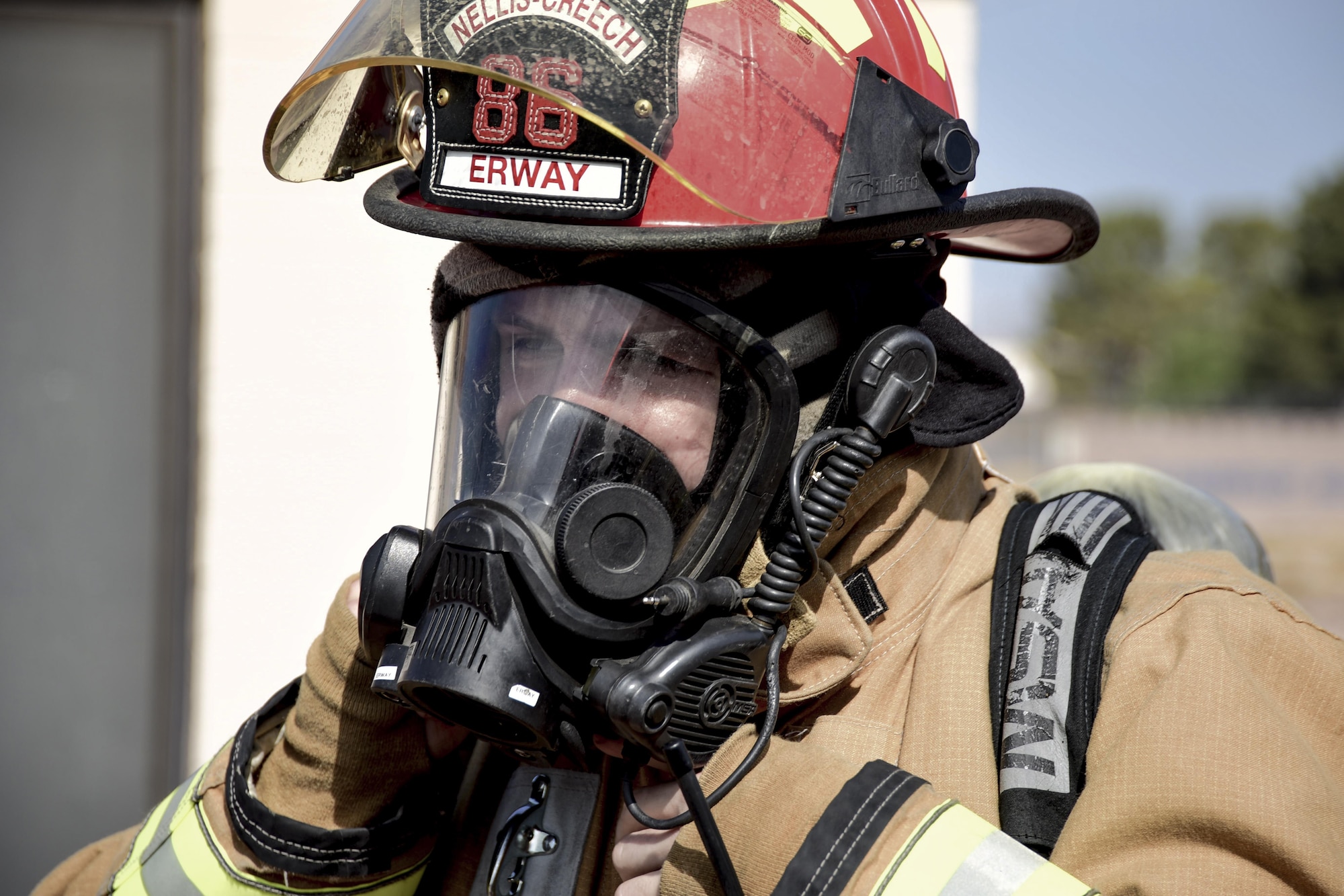 Staff Sgt. Blaine Erway, 99th Civil Engineer Squadron firefighter crew chief, adjusts his gas mask before entering a simulated house fire during Red Flag 17-3 at Nellis Air Force Base, Nev., July 18, 2017. Red Flag helps the firefighters train on and off the flightline to put their life-saving skills to the test. (U.S. Air Force photo by Airman 1st Class Andrew D. Sarver/Released)