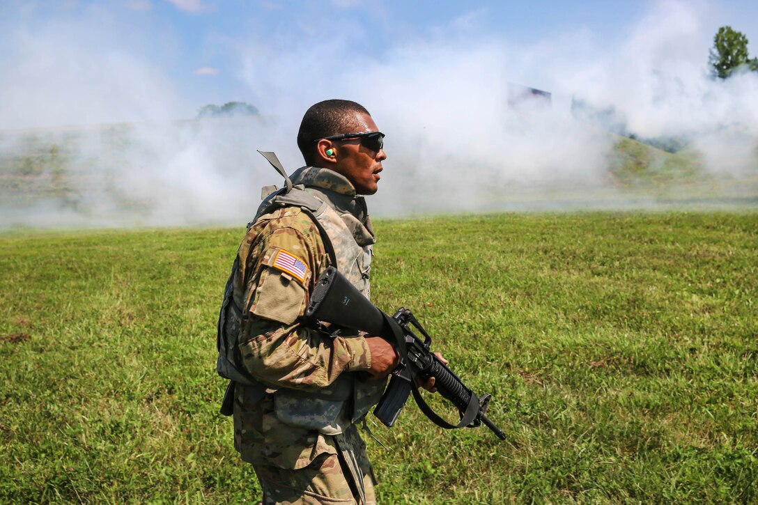 Army Staff Sgt. Qujuan Baptiste advances as concealment smoke blows across the range during a stress shoot at Camp Atterbury, Ind., July 18, 2017, as part of Army Materiel Command's Best Warrior Competition. Baptiste is assigned to the Army Sustainment Command. Army photo by Sgt. 1st Class Teddy Wade 