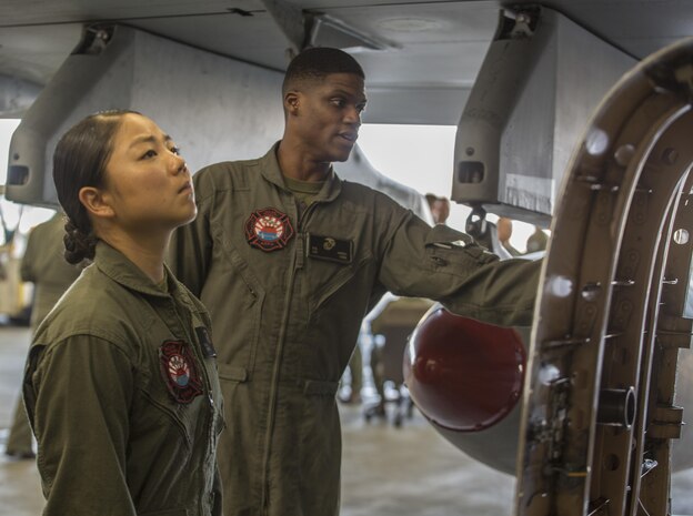 U.S. Marine Corps Sgt. Rodney Harris, right, an aircraft rescue firefighter with Headquarters and Headquarters Squadron (H&HS), explains to Lance Cpl. Dahee Park, an aircraft rescue firefighter with H&HS, how to put out an external fire on an F/A-18C Hornet at Marine Corps Air Station Iwakuni, Japan, July 19, 2017. Aircraft Rescue and Firefighting Marines visited the display to familiarize themselves with the aircraft so they can be more efficient in emergency situations. (U.S. Marine Corps Lance Cpl. Gabriela Garcia-Herrera)