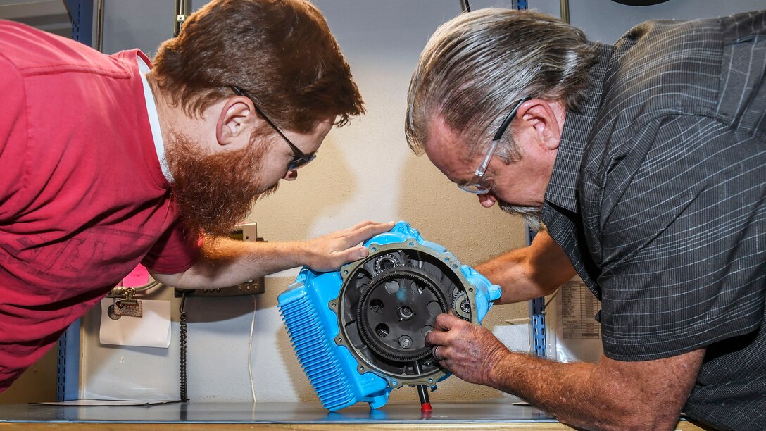 Mechanical Engineer Vance Bowman, left, and Equipment Specialist Rick Blickfeldt, both 419th Supply Chain Management Squadron, examine an A-10 aircraft Auxiliary Power Unit gear box at Hill Air Force Base, June 23. (U.S. Air Force)